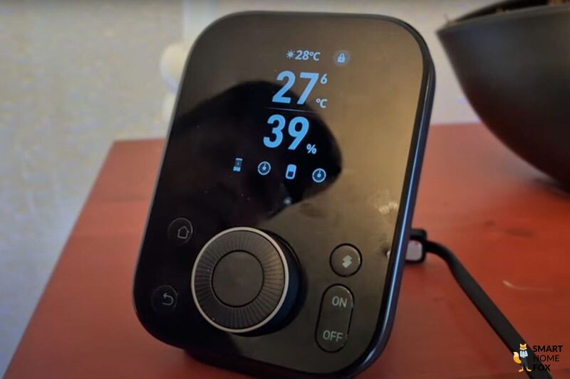 SwitchBot Hub 3 steht auf einem Tisch - kompakt, modern, mit Drehregler und Sensoranzeige.